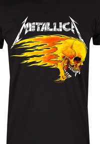 Black T-shirt featuring bold yellow and orange skull graphic with flames. The design includes the word "Metallica" in white distressed lettering.