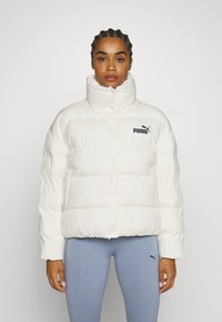 White puffer jacket with high collar, featuring black Puma logo. Quilted design with a boxy shape and smooth texture.