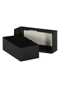 Schwarze rechteckige Box mit einer transparenten Öffnung, die gerollte schwarze Socken mit grünen Akzenten enthält. Glatte, matte Oberfläche, minimales Design.