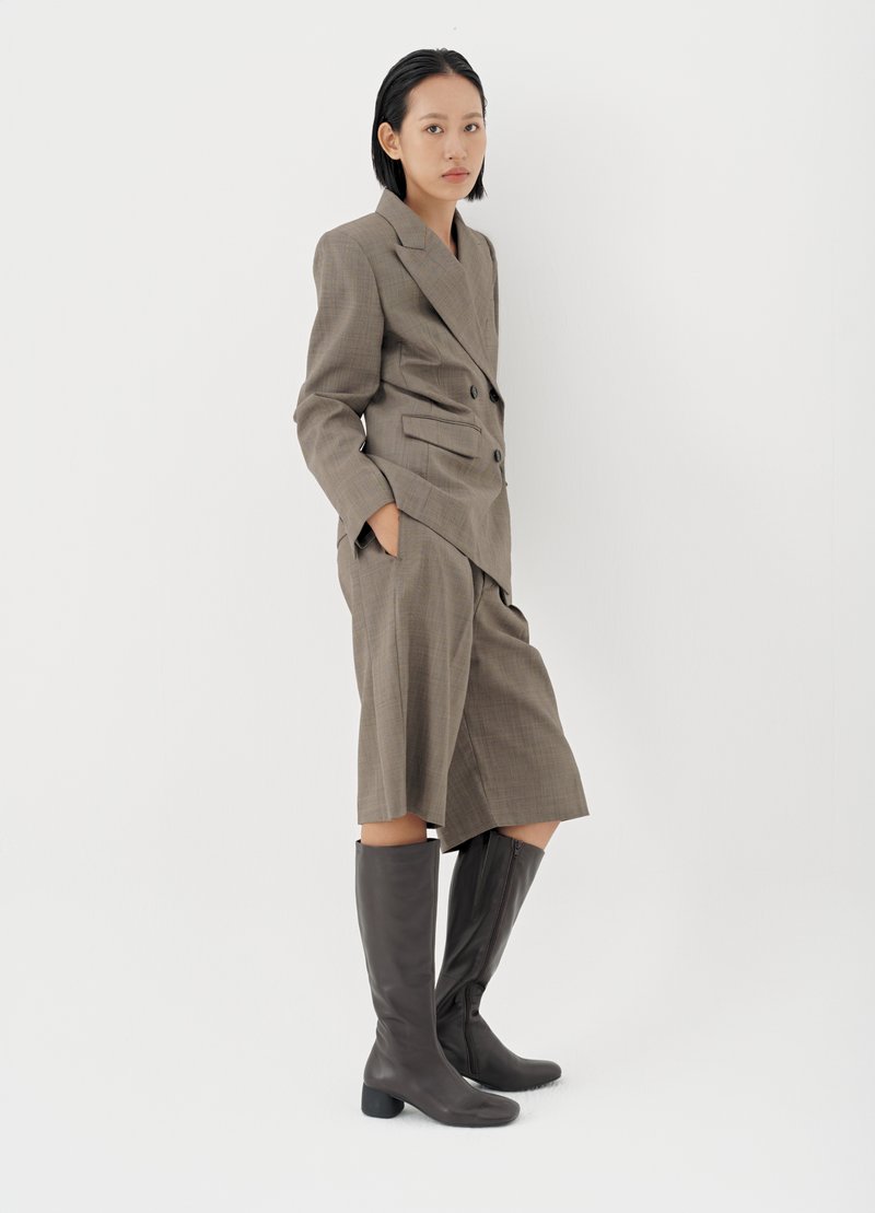 Καφέ καρό διπλό σακάκι συνδυασμένο με σορτς μέχρι το γόνατο, ολοκληρωμένο με ψηλές καφέ δερμάτινες μπότες με τετράγωνο τακούνι.