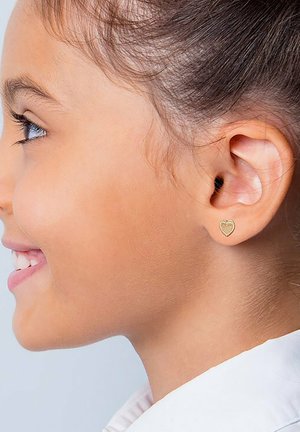 Gouden hartvormige studoorbel gedragen in een geperforeerd oor, met een gestructureerd oppervlak en een gepolijste afwerking, wat het delicate ontwerp versterkt.