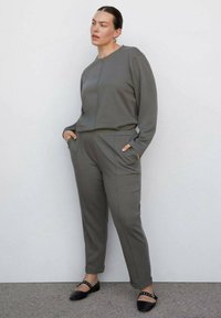 Grijze sweatshirt en bijpassende broek van zachte stof, met zijzakken. Accentueert met zwarte flats met studded details.