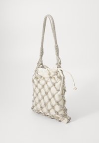 Sac fourre-tout en crème avec une superposition en maille argentée. Il dispose d'une fermeture à cordon et d'une anse tressée, alliant texture et structure.