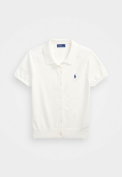 Bílá polokošile s krátkým rukávem vyrobená z bavlny, s knoflíkovým zapínáním v přední části, klasickým límečkem a malým modrým logem na levé části hrudi.