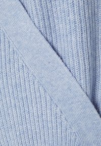 Tejido de punto azul claro con estrías verticales. Textura suave, con una banda ancha y plana superpuesta al punto.