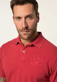 Červené bavlněné polo tričko s límečkem, na levé straně hrudi s jemně embosovaným logem "AIR RACE LEGEND INDUSTRY".