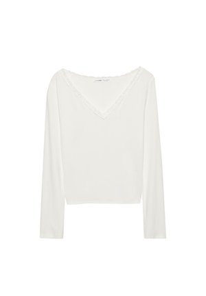 Fehér hosszú ujjú felső V-nyakkivágással, csipkével díszített gallérral. Simább textúra és laza szabás.