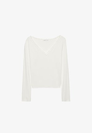 Biała bluzka z długim rękawem i dekoltem w kształcie litery V, ozdobiona koronkową lamówką wokół kołnierza. Gładka faktura i luźny krój.