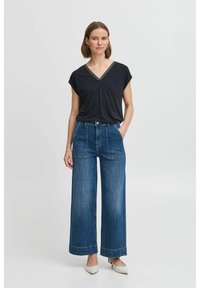 Black V-neck top with short sleeves, paired with light blue wide-leg denim pants featuring front pockets and rolled cuffs.