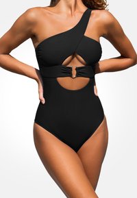 Czarny jednoczęściowy strój kąpielowy z asymetrycznym krojem na jedno ramię, wycięciem na wysokości talii oraz małym metalowym akcentem na środku. Gładka faktura.