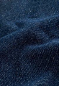 Tume sinine denimpind koos sujuva tekstuuriga, millel on peened värvimuutused ja tihe kude. Kortsud lisavad sügavust.