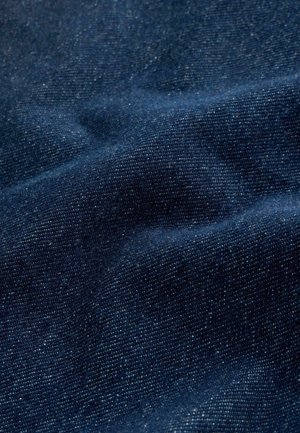 Tessuto di denim blu scuro con una texture liscia, caratterizzato da leggere variazioni di colore e un motivo di tessitura fitta. Le pieghe creano profondità.