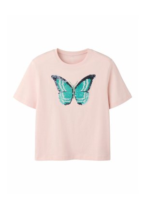 T-shirt rose clair à manches courtes avec un grand papillon en sequins bleu et noir centré sur le devant.