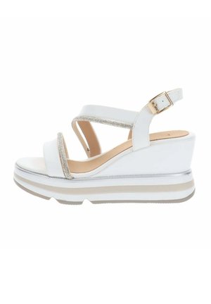 Sandale compensée blanche avec semelle plateforme, deux fines brides ornées de strass, bride de cheville avec boucle dorée et semelle intérieure beige rembourrée.