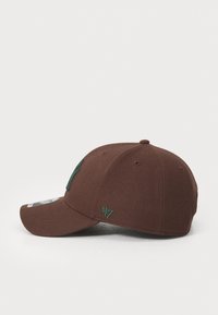Brun hat med en buet skygge, lavet af struktureret stof. Har et grønt broderet logo og accenter. Inkluderer et sideskilt med brandlogo.