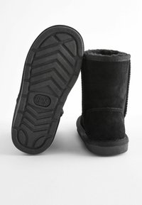 Schwarze Wildlederschuhe mit einer strukturierten Gummisohle, versehen mit einem weichen Futter, genähten Akzenten und einer geschwungenen Oberkante.