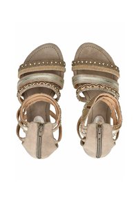 Beige Sandalen mit mehreren dekorativen Riemen, featuring metallischen Akzenten, strukturiertem Stitching und einem Reißverschluss hinten.