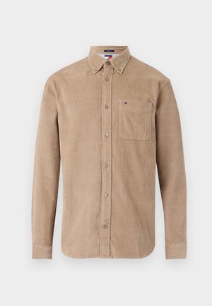 Camisa de corduroy castanho com mangas longas, frente com botões, colarinho pontiagudo e um único bolso no peito. Apresenta um pequeno logótipo no bolso.