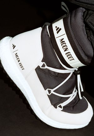 Witte en zwarte Moon Boot met een gewatteerd ontwerp, textuurbovenkant, ronde veters en een rubberen loopvlak met een duidelijk profiel.