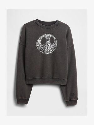 Tumehall cropped-sviiter, mille esiosas on ringikujuline valge kolju muster, mis moodustab suure ümmarguse näo ja varrukaäärel on väike "GAP" logo.