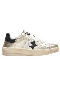Sneaker metallic oro con tallone nero, design di stelle bianche e nere, lacci bianchi e suola testurizzata. Usura leggera visibile sulla suola.