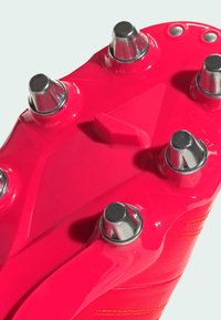 Suela de bota de fútbol en un brillante color rosa con tacos metálicos plateados y detalles texturizados. Superficie suave y brillante con un diseño angular.