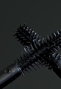 Schwarzer Mascara-Applikator mit doppelten Borsten, langen, stacheligen Borsten und einem strukturierten Griff. Verfügt über zwei Zinken für eine präzise Anwendung.