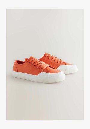 Baskets en toile orange avec semelles et capuchons en caoutchouc blancs, dotées de lacets plats et d'un minimum de détails pour un design classique.