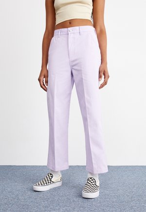 Lilac wide-leg pants with a button closure, featuring a smooth texture and straight cut. Paired with black and white checkered slip-on shoes.