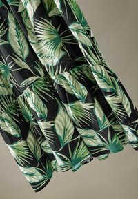 Zwarte jurk met een groen palmblaadjespatroon, geplooid ontwerp en ruches aan de zoom. Gemaakt van lichte stof met een gladde textuur.