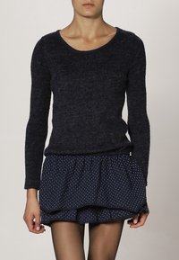 Námořnický pletený svetr s kulatým výstřihem, zkombinovaný s námořnickou mini sukní s puntíky a vrstveným volánkem.