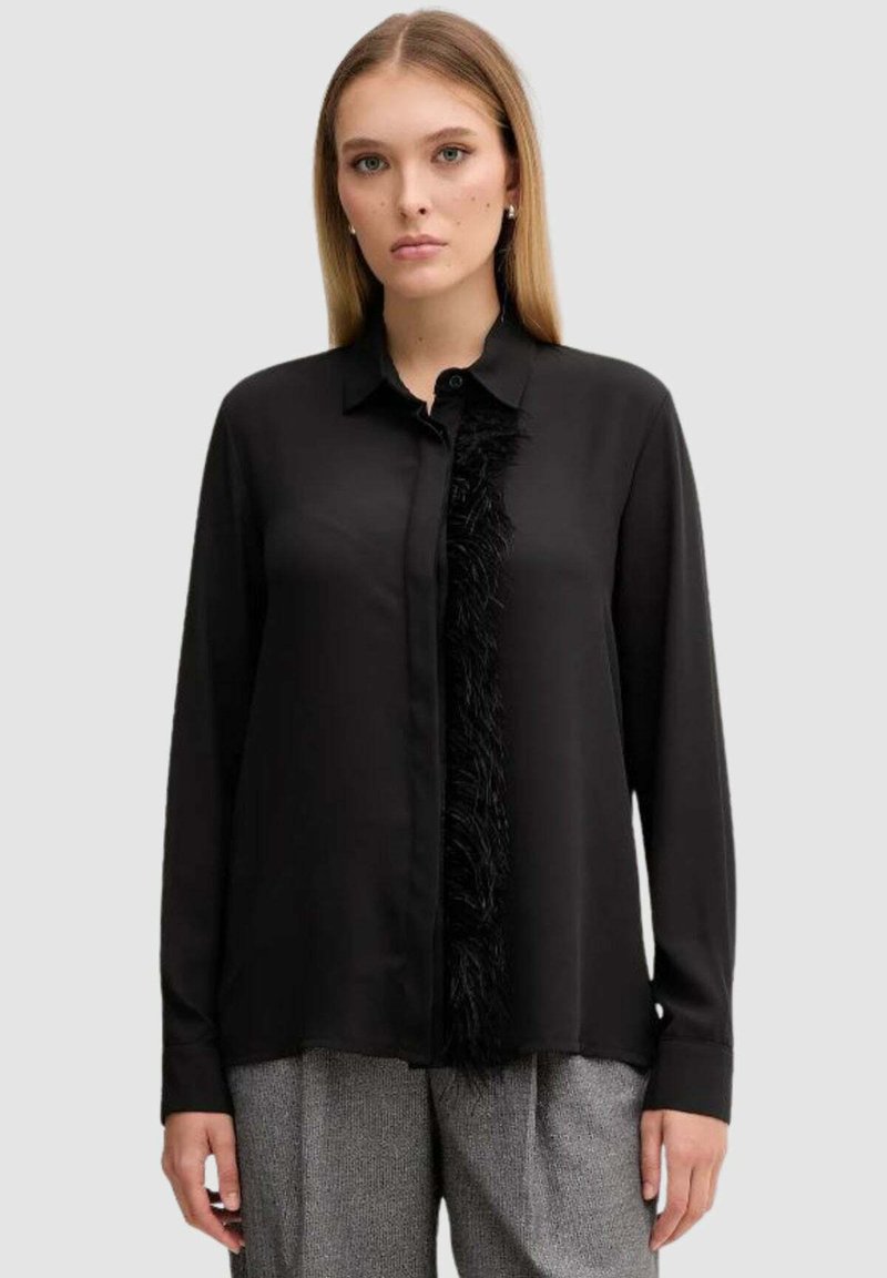 Blusa nera a maniche lunghe con dettaglio a frange testurizzate lungo la parte anteriore, con collo a camicia con bottoni e tessuto liscio simile al raso.