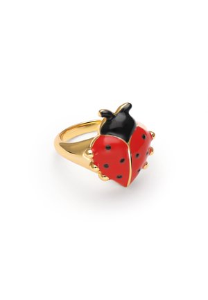 Anillo de oro con diseño de mariquita esmaltada en rojo y negro, con manchas negras y detalles redondeados en oro sobre un fondo blanco.