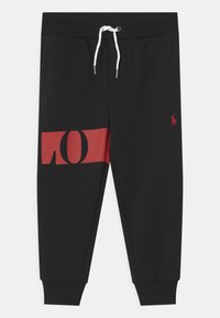 Svarta sweatpants i bomull med ett rött grafiskt tryck på sidan och en liten röd logotyp. Har elastisk midja och muddar.