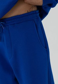 Blauwe katoenen joggingbroek met een elastische tailleband met trekkoord, zijzakken en een zachte textuur, met zichtbare stiksel details.