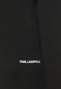 Svart sweatshirt i bomullsmix, med en mjuk textur och ribbad fåll. "KARL LAGERFELD" logotyp i vitt i nedre vänstra hörnet.
