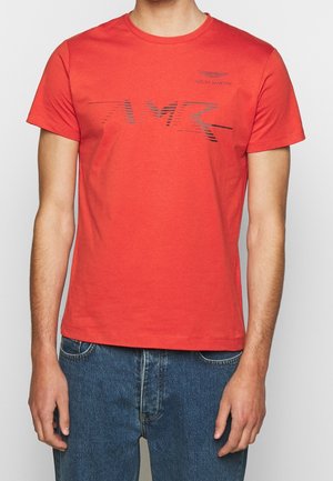 Czerwona bawełniana koszulka z okrągłym dekoltem. Na przodzie znajduje się czarny logo Aston Martin oraz graficzny wzór "AMR". Krótkie rękawy, dopasowany krój.