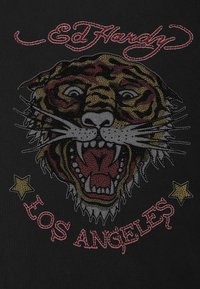 Camiseta negra con un gráfico de tigre colorido que presenta ojos detallados, boca abierta y acentos de estrellas, con la marca "Ed Hardy" y "Los Ángeles".