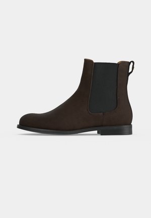 Bottine Chelsea en daim marron foncé avec panneau latéral élastique noir et petit talon noir, présentée de profil sur fond blanc.
