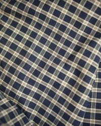 Pamukasta tkanina s tamnoplavim i kremasto-bijelim kariranim uzorkom, s ravnomjerno raspoređenim linijama koje stvaraju mrežastu teksturu.