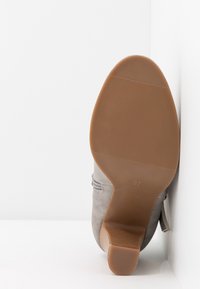 Bota de tobillo de ante gris con suela de goma, con un patrón texturizado y una cremallera lateral. Talla 37 indicada en la suela.