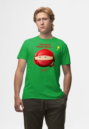 Grøn kortærmet T-shirt med en tegneserie-ninja med en rød maske, der smiler, og teksten "DETTE KAN MÅSKE LYDE KLICHÉ" ovenfor.