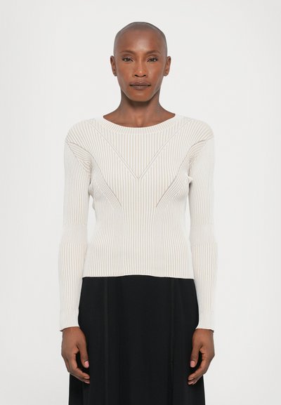 Lysefarvet ribbet langærmet sweater med bådudskæring, prydet med geometriske mønstre og teksturerede detaljer, parret med en sort nederdel.