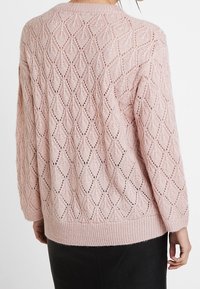 Maglione rosa chiaro lavorato a maglia con un motivo a diamante, orlo e polsini a coste, vestibilità comoda e texture a trama aperta.