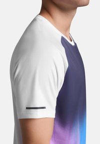 Camisa de manga corta con un cuerpo blanco y un diseño en degradado que va de un púrpura oscuro a azul, con un acento negro en la manga.