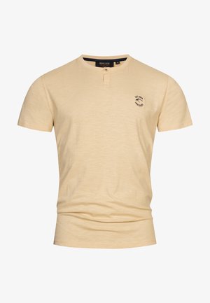 Beige T-shirt med korte ærmer, tekstureret overflade, rund hals, knaplukning og et lille sort logo på venstre bryst.