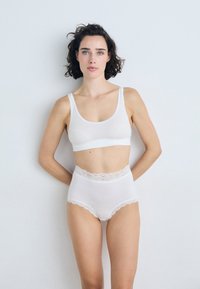 White cotton sports bra with wide straps and lace accents; high-waisted matching underwear with lace trim, smooth texture and seamless design.