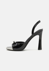 Black patent leather high-heel sandal with open toe, slingback strap, silver metallic toe cap, and decorative buckle detail.