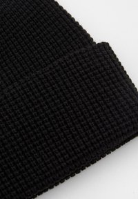 Mustat neulottu pipo texturoituneella ribbikuvioilla. Sisältää käänteisen helman ja tiheän, lämpimän neulekankaan eristykselle.