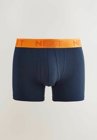 Tengerészkék pamut boxeralsó narancssárga gumiszalaggal, melyen a "NEXT" felirat jól láthatóan szerepel az elülső részen.